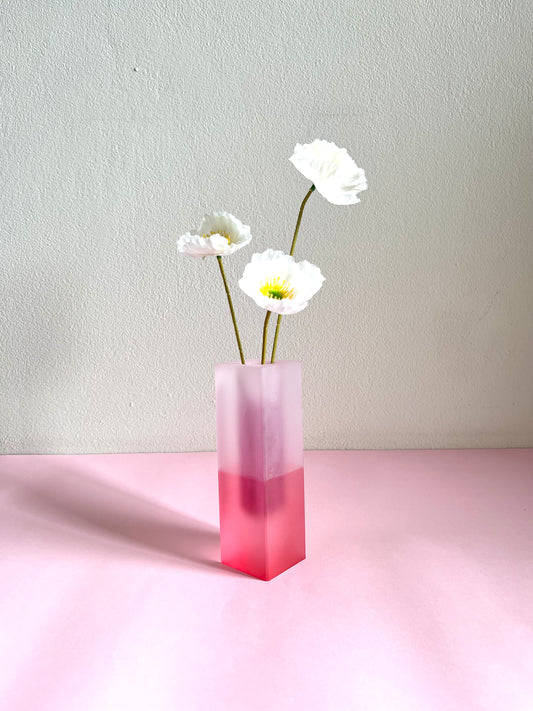 Pink gradient vase with white flowers on a light pink surface