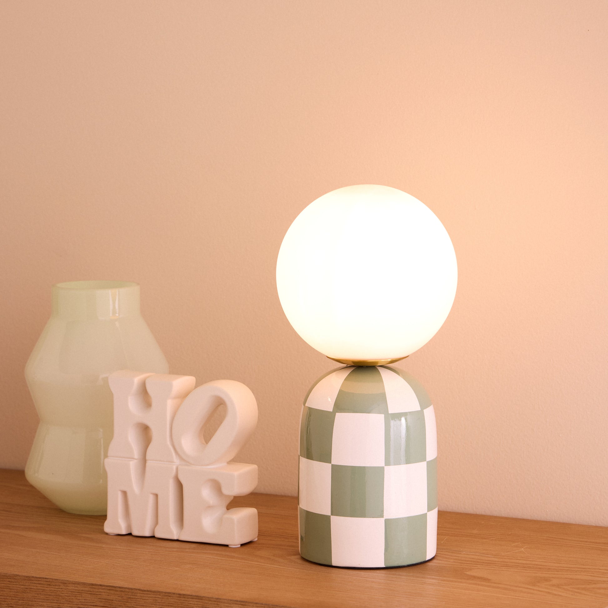 Archie green and white table lamp lit on a timber console