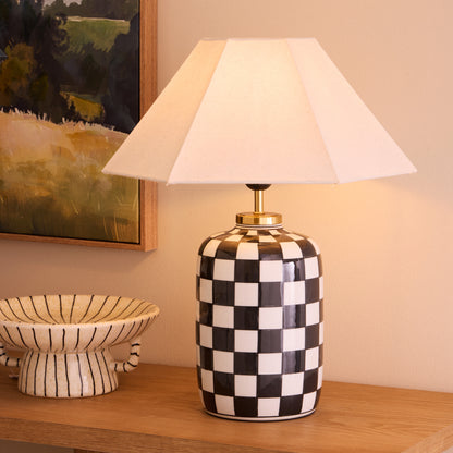 Haynes checkerboard table lamp lit on a timber console