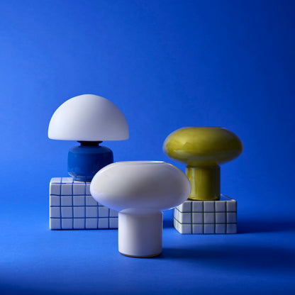 Teyo green glass table lamp styled with sculptural lamps on a blue background